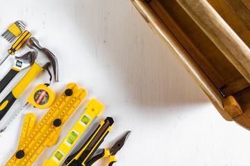 Set of yellow woodworking tools with wooden tool box on white background. Top view.