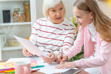 Senior woman teaching her pretty granddaughter drawing