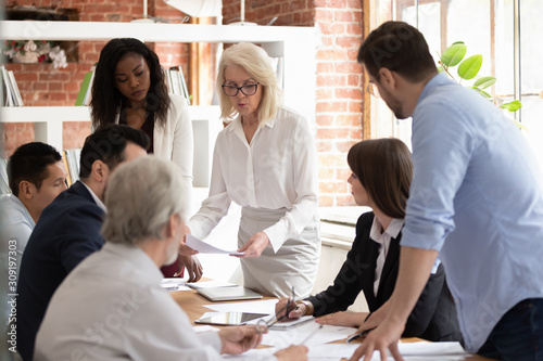 Fotomural Diverse team and aged boss do paperwork analyzing financial report