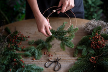 Woman making Christmas wreath of spruce, step by step. Concept of florist's work before the Christmas holidays..