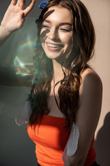 Wall Mural - smiling boho girl with braids in hairstyle posing on grey with lens flares