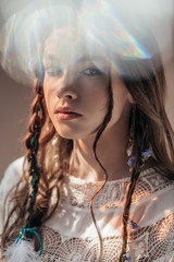 Wall Mural - beautiful girl with braids in hairstyle posing in white boho dress on grey with lens flares