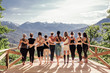 canvas print picture - Rear view of a group of slim body-positive sportive active friendly women doing fitness and yoga together among mountain ecologically clean nature. Ecological Sports Tourism Concept