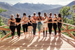 canvas print picture - Rear view of a group of slim body-positive sportive active friendly women doing fitness and yoga together among mountain ecologically clean nature. Ecological Sports Tourism Concept