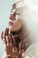 Wall Mural - beautiful tender girl with braids in hairstyle posing in white boho dress on grey with lens flares