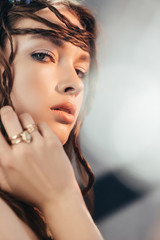 Wall Mural - tender boho girl with braids in hairstyle posing on grey with lens flares