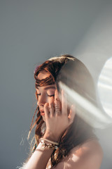 Wall Mural - tender nude boho girl with braids in hairstyle posing on grey with lens flares