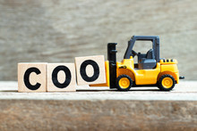 Toy Forklift Hold Letter Block O To Complete Word COO (abbreviation Chief Operating Officer) On Wood Background