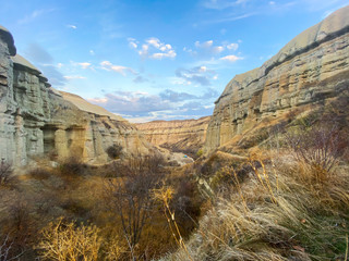 Wall Mural - View of a valley filled with ancient rock formations. Blue sky, white clouds. Landscape. Cappadocia, Turkey. 12 05 2019