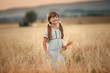 © ElenaBatkova - A girl with spikelets in her hands and braids in her hair in a wheat field.