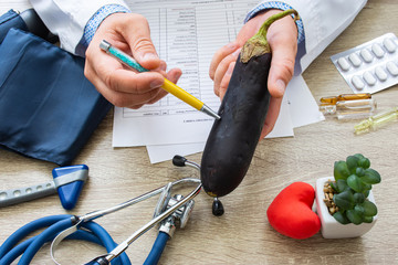 Doctor nutritionist during consultation held in his hand and shows patient eggplant or aubergine. Counseling and explanation of use of eggplant in food and diet, health benefits, effect on body