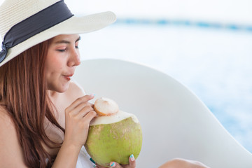 Portrait of a beautiful woman relaxing with coconut juice at the swimming pool outdoors