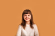 © Marharyta Hanhalo - Cute cute girl on an orange background smiling while looking at the camera. Happy baby face, portrait of a charming kid, joy and fun, lifestyle.