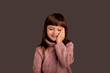 © Marharyta Hanhalo - Happy smiling pretty child girl in pink sweater over gray background. Active beautiful childhood time, happy expression. Palm on face, cute, charming face. Baby face. Lifestyle concept.