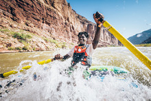 Man Rafting Through Nevills Rapid In Colorado River