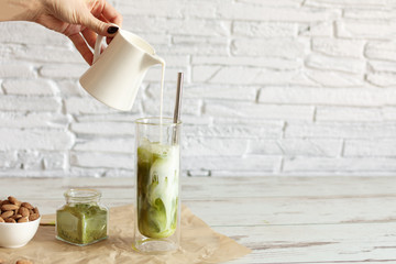 Green tea matcha iced latte with almond milk on light background.