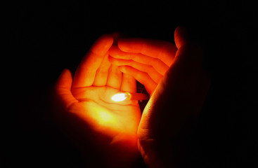 Wall Mural - a lighted candle in the hands of a girl