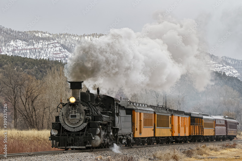 Vintage Steam Train Billowing Smoke as it Moves Through the Mountains. - obrazy, fototapety, plakaty 