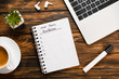 © LIGHTFIELD STUDIOS - notebook with new years resolutions lettering near laptop, wireless earphones, felt-tip pen, plant and coffee cup on wooden desk