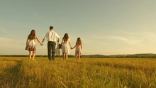 Concept Of A Happy Childhood. Mother, Father And Little Daughter With Sisters Walking In Field In Sun. Happy Young Family. Children, Dad And Mom Play In Meadow In Sunshine. Concept Of Happy Family.