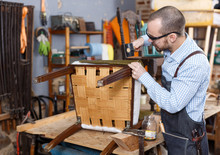 Craftsman Reupholstering Chair In Workshop