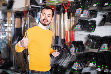 Wall Mural - Man choosing various tools in garden equipment shop