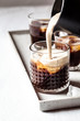 © Westend61 - Close up of milk pouring over iced coffee