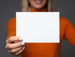 A smiling teen girl holds big blank paper sheet mockup with space for your text