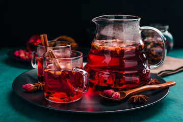 Fresh brewed spicy fruit tea with herbs, rose flowers, apples and cinnamon, hot healthy drink, dark mood beverage