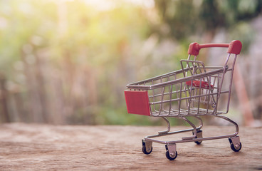 Shopping concept - empty shopping cart on brown wood table. online shopping consumers can shop from home and delivery service. with copy space.