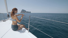 Beautiful Woman On A Yacht Enjoys The Journey On The Background Of The Islands Of Ibiza Or Mallorca. Luxury Yacht Near The Balearic Islands