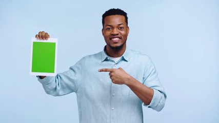 positive african american man showing digital tablet isolated on blue