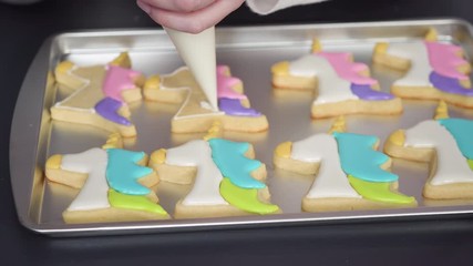 Sticker - Decorating unicorn sugar cookies with multi-color royal icing.