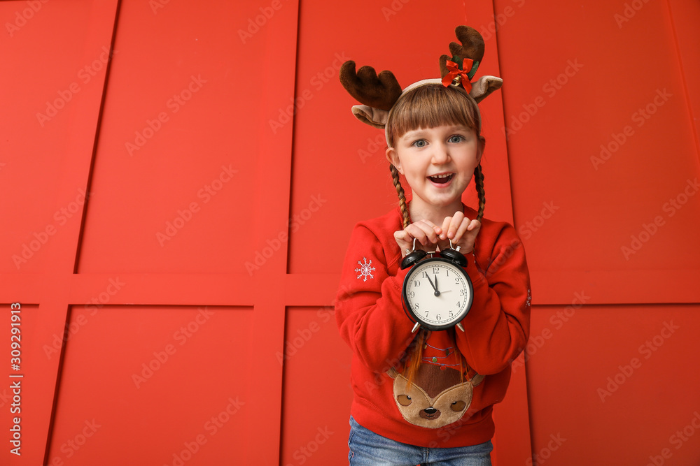 Little girl with alarm clock on color background. Christmas countdown concept