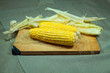 Patch of corn peeled on a wooden board on a fabric background. Two pieces