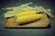 Patch of corn peeled on a wooden board on a fabric background. Two pieces