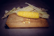 Patch of corn peeled on a wooden board with grains on a fabric background. Vignette