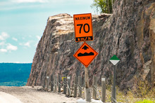 Temporary Condition Road Signs, An Orange Sign Shows The Maximum Safe Speed Is 70 Km With Bump Or Uneven Pavement On The Road Ahead Sign On Roadside