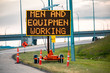 Temporary condition Variable message sign with orange barrels on the right roadside, Men and equipment working, work zone on the Canadian roads