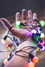 Hand With Colored Christmas Garland.