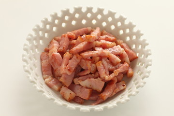 Fried bacon in white bowl on white background with copy space