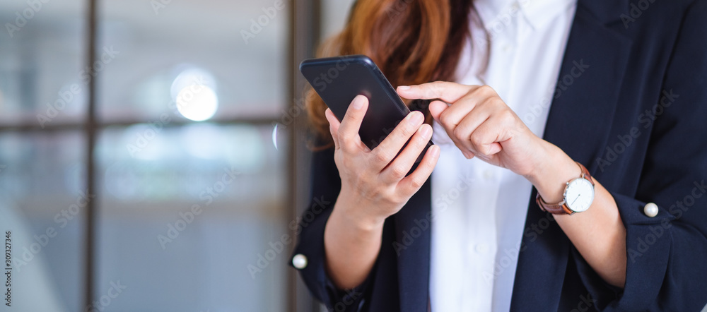 Closeup image of a businesswoman holding and using mobile phone - obrazy, fototapety, plakaty 
