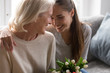 © fizkes - Loving adult daughter greeting mom with flowers
