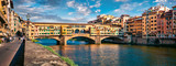 Panoramic view of medieval arched river bridge with Roman origins - Ponte Vecchio over Arno river. Colorful summer cityscape of Florence, Italy, Europe. Traveling concept background.