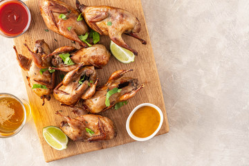 Wall Mural - Baked quail with sauces, lime and beer on a wooden board.