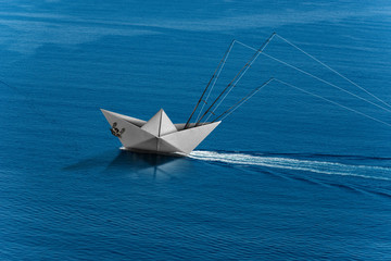 Wall Mural - Big game fishing concept. Paper trolling boat with three fishing rods in the blue sea with wake, photography