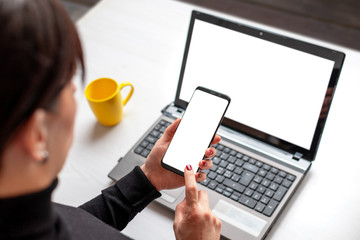 Poster - Phone and laptop mockup. Woman holding smart phone with isolated screen over the laptop with isolated screen for app or web site presentation