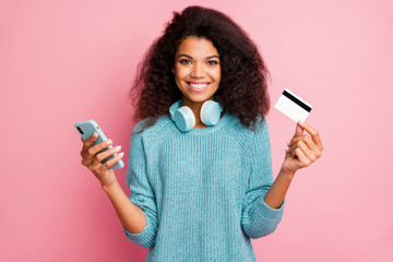 Wall Mural - Close-up portrait of her she nice attractive lovely cheerful cheery wavy-haired girl holding in hands cell bank card wireless purchase buying shopping online isolated over pink pastel color background