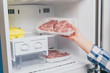 cropped view of woman taking out frozen meat from freezer