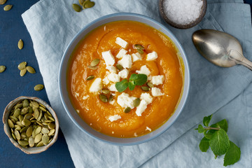 Wall Mural - Pumpkin cream soup with sheep cheese, autumn homemade food, dark blue background, top view. Fodmap diet, lchf. Vegetarian menu, clean eating recipe